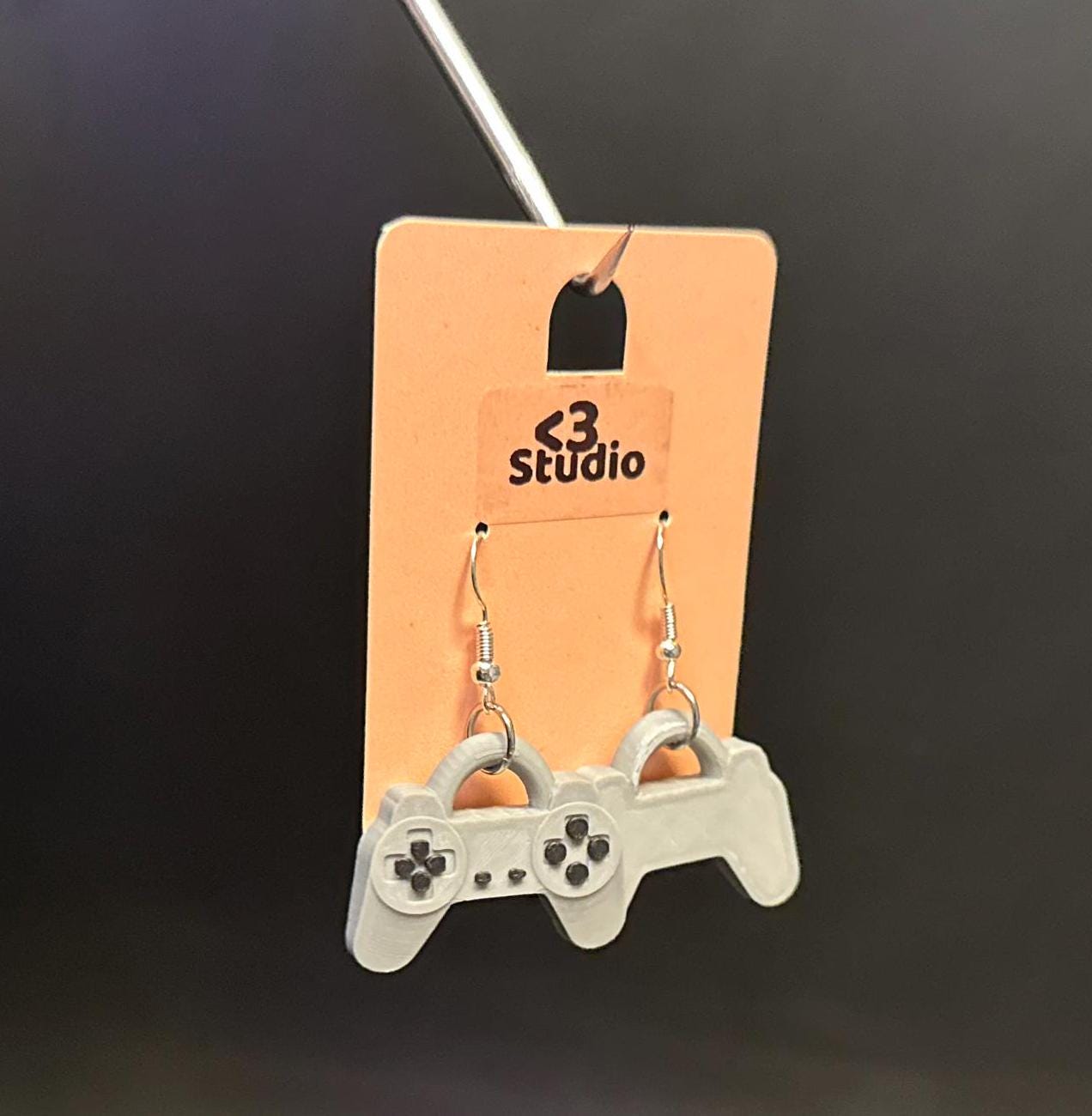 PS1 controller-inspired earrings with intricate details, perfect for gamers and retro gaming enthusiasts. Lightweight and unique design for a nostalgic touch.