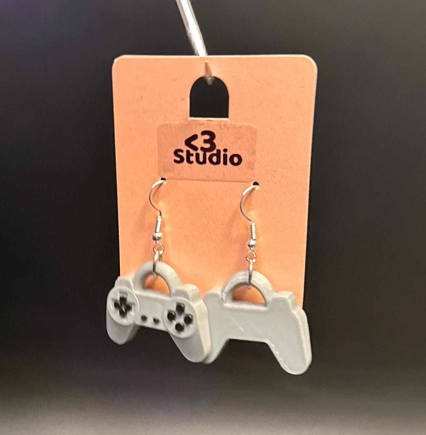 PS1 controller-inspired earrings with intricate details, perfect for gamers and retro gaming enthusiasts. Lightweight and unique design for a nostalgic touch.
