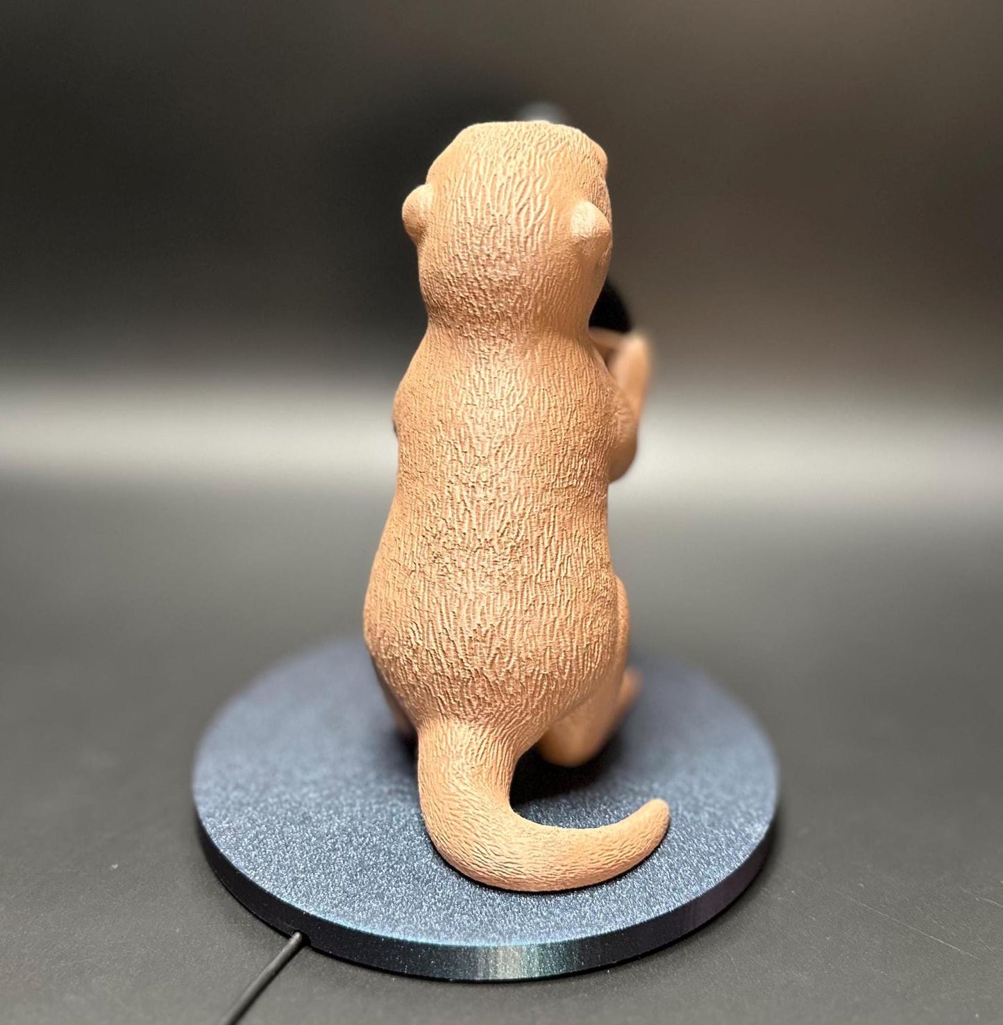 A cute gray otter figure holding a magnetic phone charger dock. Functional and adorable addition to any tech setup.β