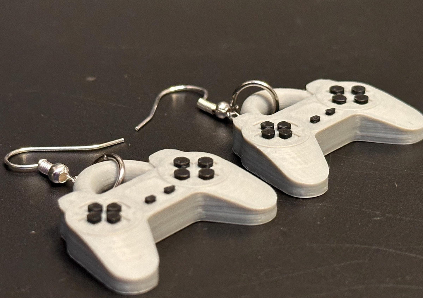 PS1 controller-inspired earrings with intricate details, perfect for gamers and retro gaming enthusiasts. Lightweight and unique design for a nostalgic touch.