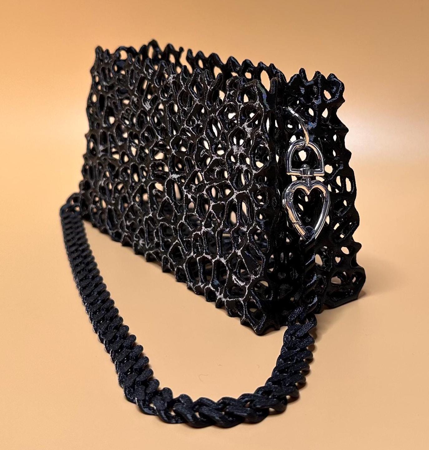 A sleek black clutch with a chain strap, suitable for gothic outfits, cosplay, or formal events.