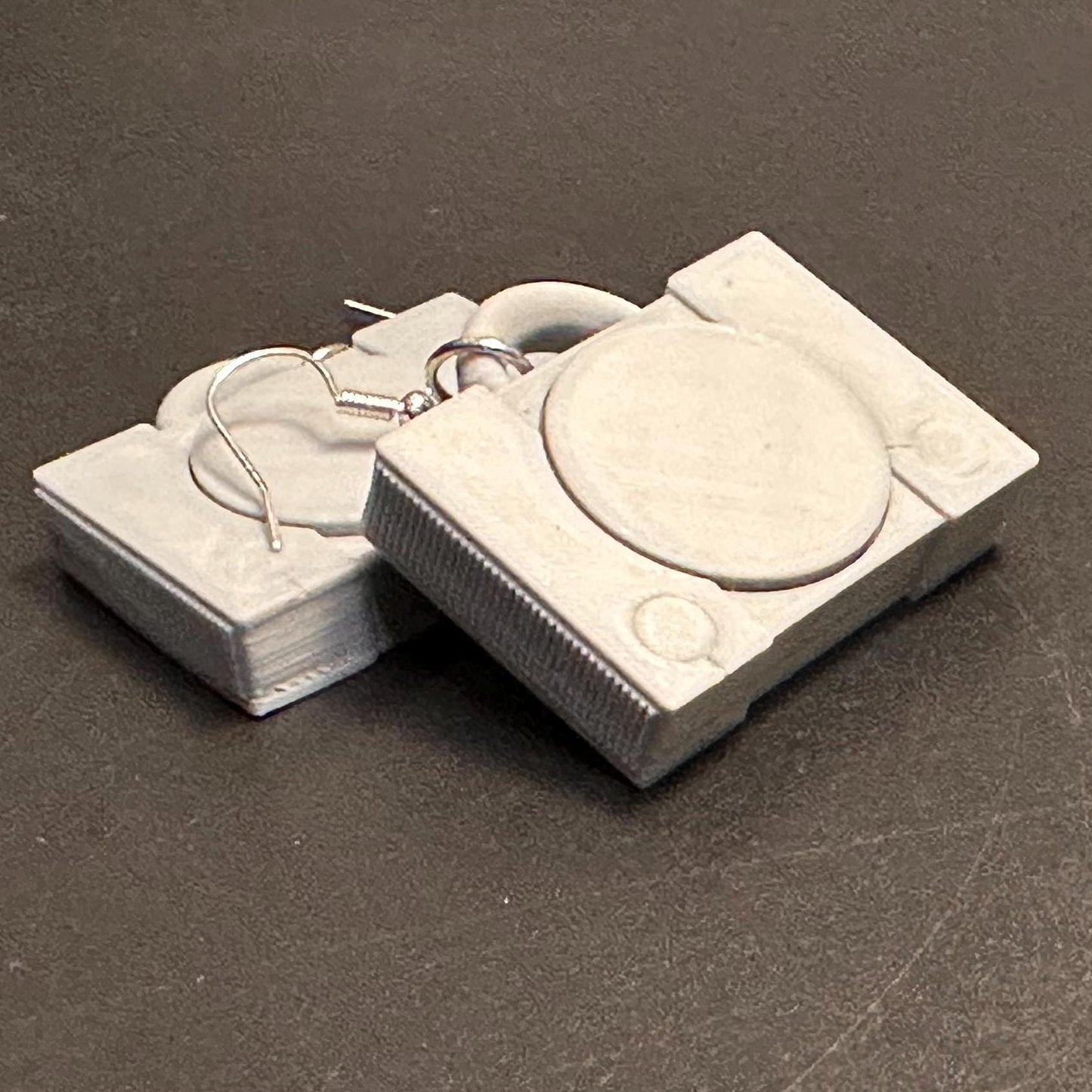 PS1 console-inspired earrings with a sleek retro design, celebrating gaming nostalgia. Lightweight and perfect for gamers and vintage enthusiasts.