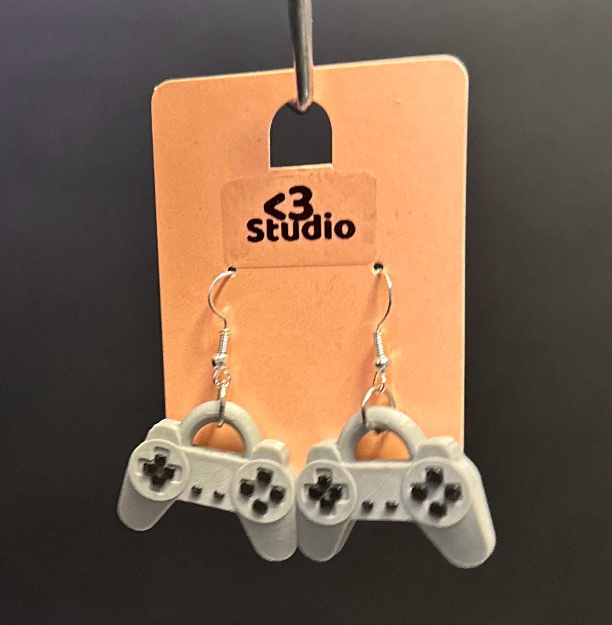 PS1 controller-inspired earrings with intricate details, perfect for gamers and retro gaming enthusiasts. Lightweight and unique design for a nostalgic touch.