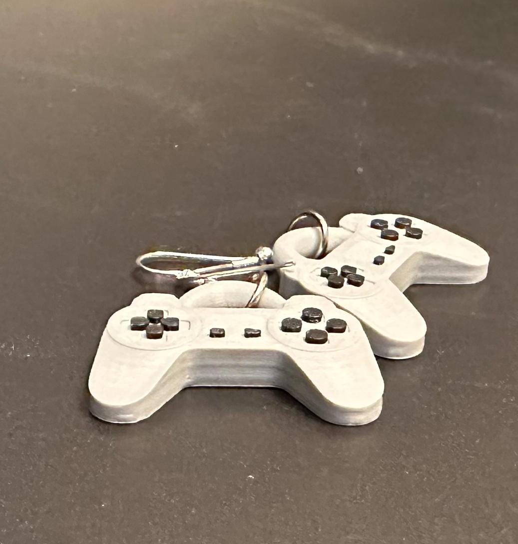 PS1 controller-inspired earrings with intricate details, perfect for gamers and retro gaming enthusiasts. Lightweight and unique design for a nostalgic touch.