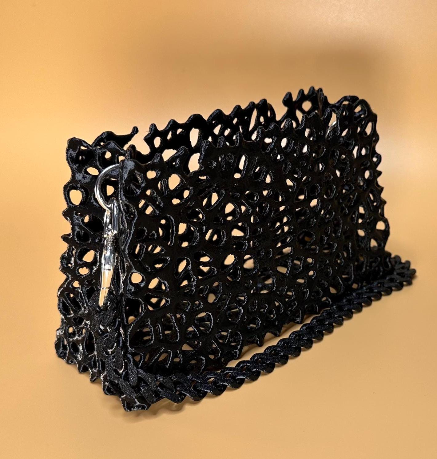 A sleek black clutch with a chain strap, suitable for gothic outfits, cosplay, or formal events.