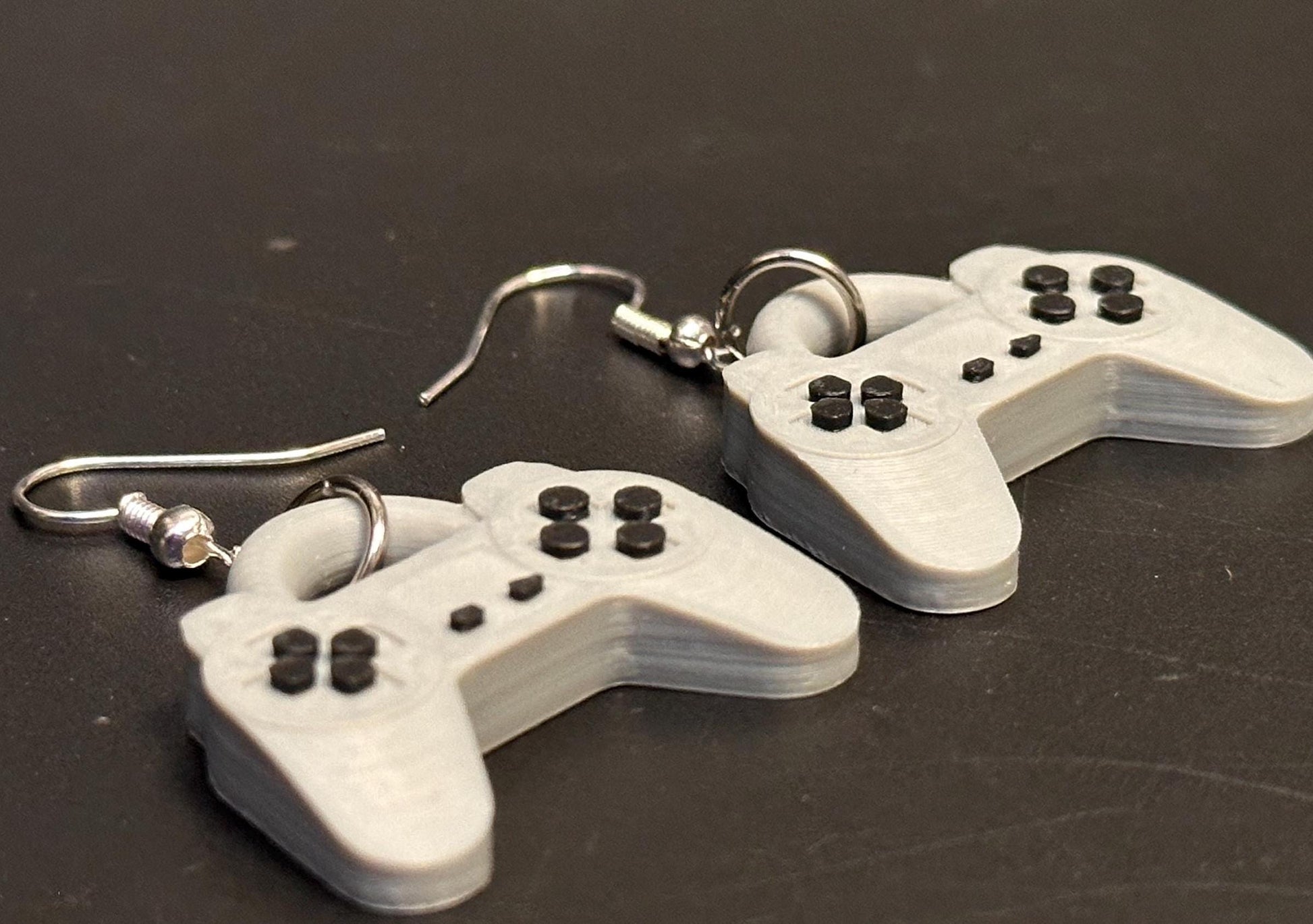 PS1 controller-inspired earrings with intricate details, perfect for gamers and retro gaming enthusiasts. Lightweight and unique design for a nostalgic touch.