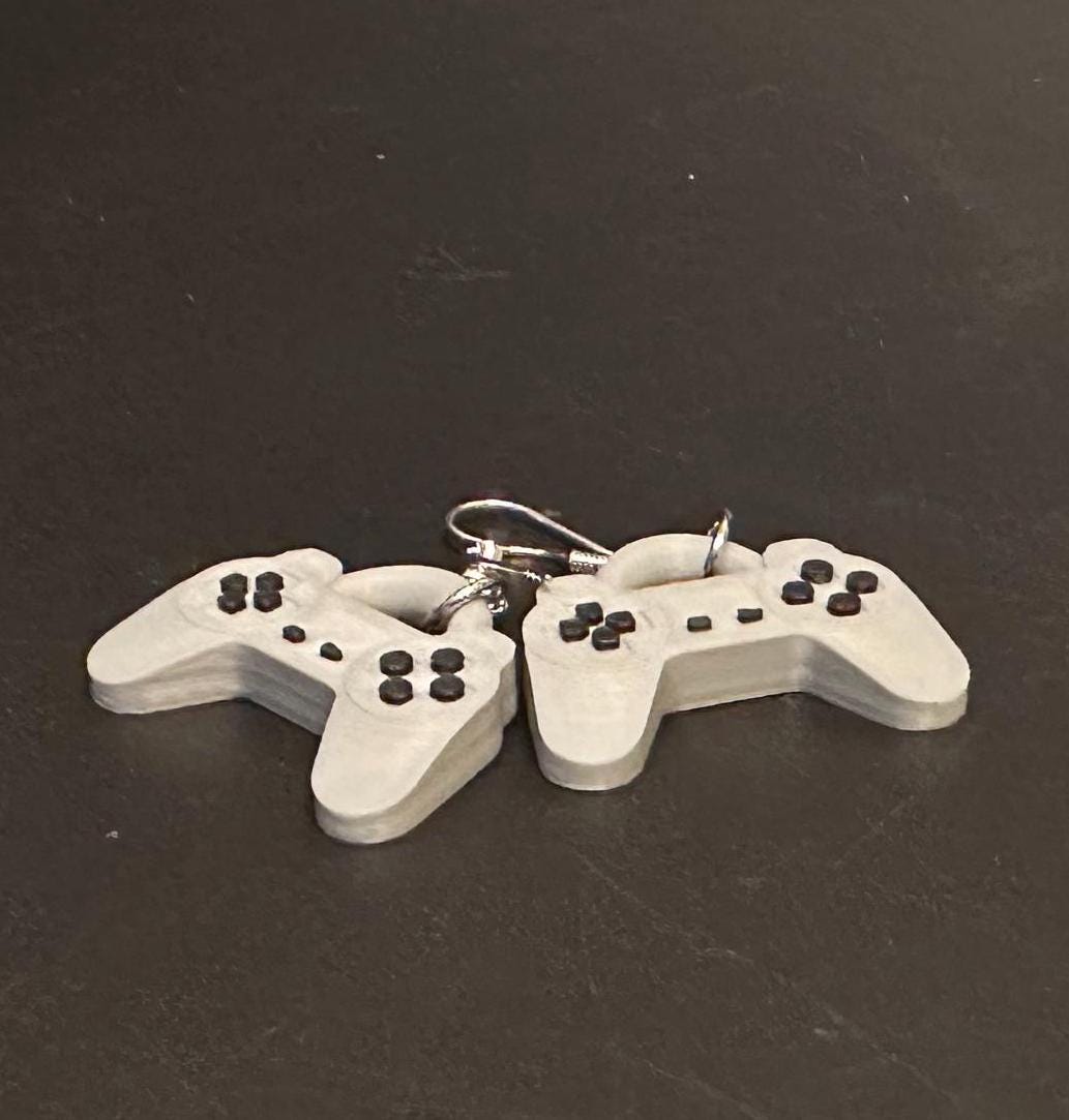 PS1 controller-inspired earrings with intricate details, perfect for gamers and retro gaming enthusiasts. Lightweight and unique design for a nostalgic touch.